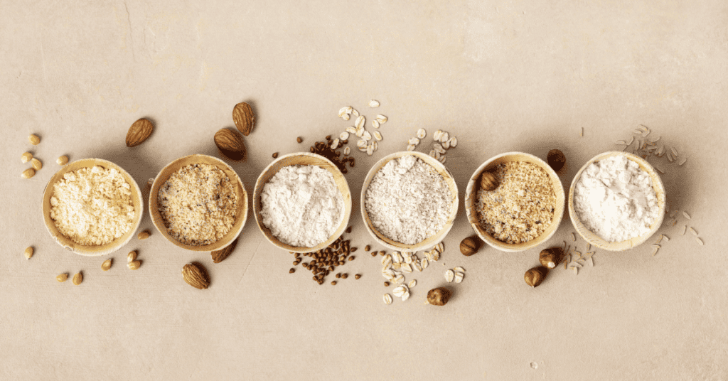 6 cups each with different types of flours including corn, almond, oat, rice and other nuts