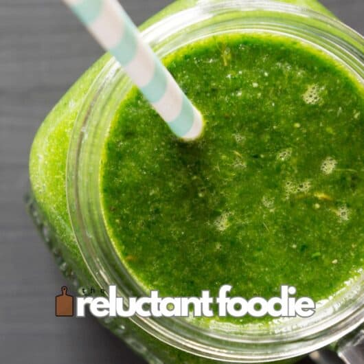 mango green smoothie in a jar with straw on counter