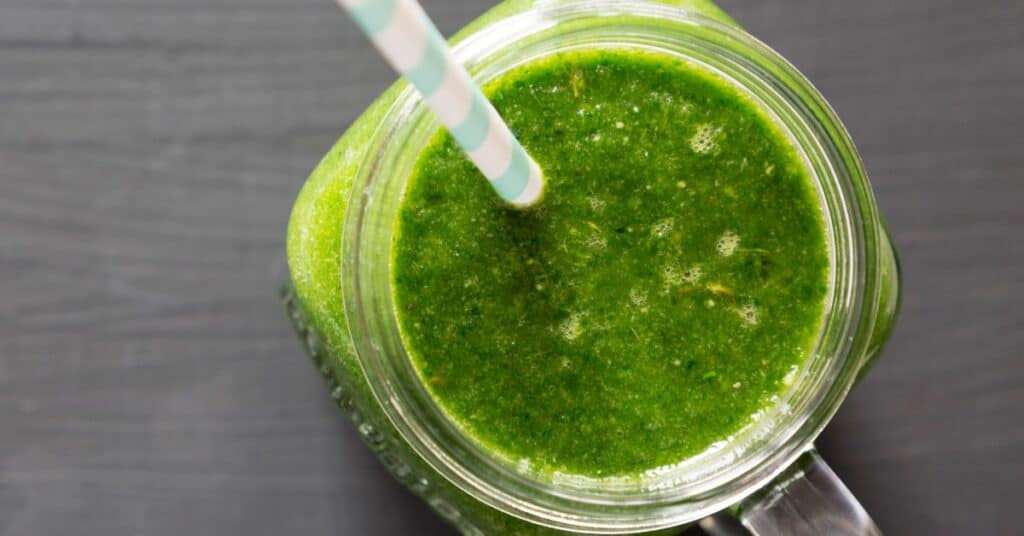 mango green smoothie in a jar with straw on counter