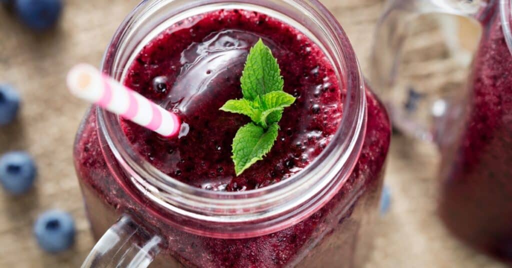 berry smoothie in mason jar with straw