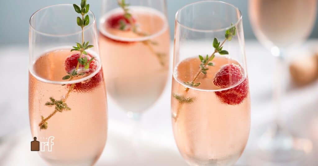 champagne mocktail with berries and thyme in glass